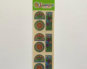 May include: A sheet of 6 colorful, prismatic, stained glass window stickers featuring a sunflower, tulips, and irises. The stickers are from SandyLion Sticker Designs.