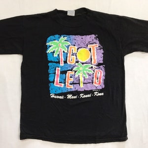 May include: Black t-shirt with a colourful graphic that says "I GOT LET'D" with palm trees and a sun. The text below the graphic says "Hawaii - Maui - Kauai - Kona".