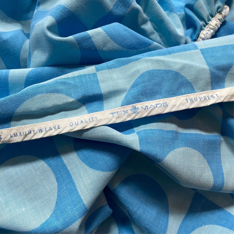 May include: Close-up of a blue and white fabric with a white label that reads "Tex Made Truprest Luxury Weave Quality".