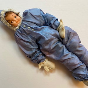 Peut inclure: Un poupon clown vintage bleu et blanc avec un col en dentelle blanche et un chapeau pointu. Le poupon a un visage peint avec des cheveux bruns et de grands yeux.