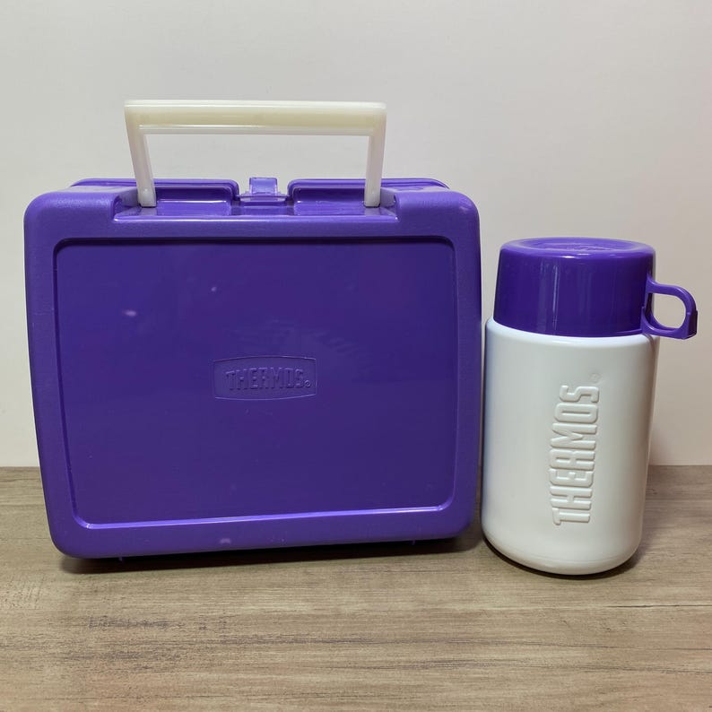 May include: Purple Thermos lunchbox with a white handle and a matching purple and white Thermos food jar.