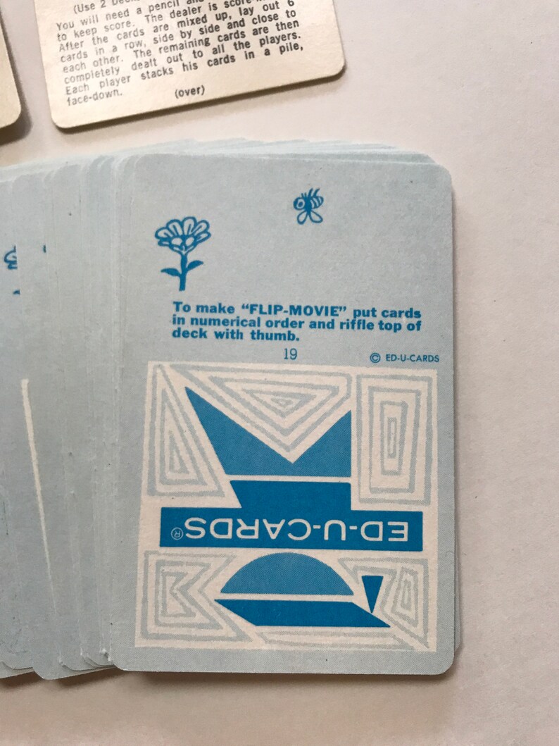 以下が含まれることがあります： 青と白のカードで、幾何学模様と青い「ED-U-CARDS」の文字が書かれています。カードには、青い小さな花と蝶も描かれています。「FLIP-MOVIE」を作るには、カードを数字順に並べて、親指でデッキの上部をシャッフルしてください。」というテキストが黒で印刷されています。テキストの下には黒で「19」と印刷されています。「ED-U-CARDS」のテキストは円の中に印刷されています。