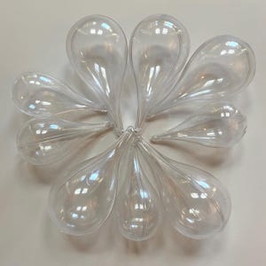 May include: Ten clear plastic teardrop-shaped ornaments. The ornaments are smooth and shiny.