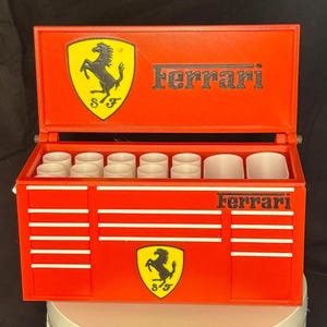 May include: Red toolbox with the Ferrari logo and the words "Ferrari" on the front and top. The toolbox has a white interior with multiple compartments.