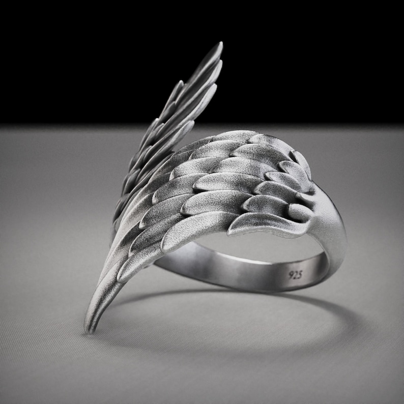 Pu&ograve; includere: Un anello color argento con un design ad ala dettagliato. L'anello presenta una superficie strutturata con dettagli di piume individuali. La fascia &egrave; liscia e timbrata con "925". L'ala si curva attorno al dito, creando un accessorio unico e artistico.