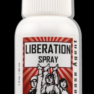May include: A white bottle with a red and white label that says "Liberation Spray Release Agent". The label features a red and white graphic of three people raising their arms in the air.