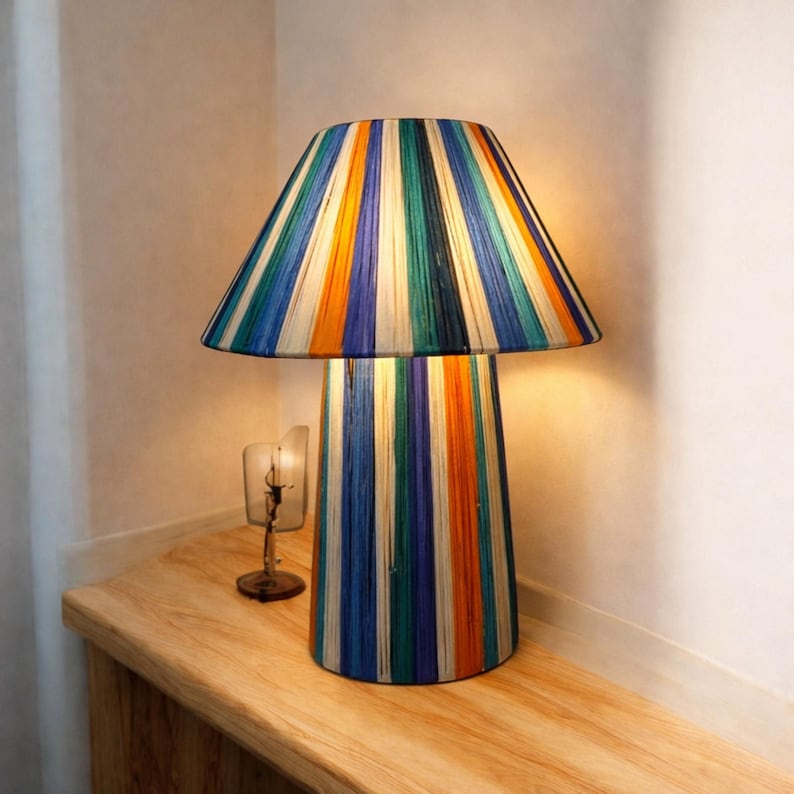 Lámpara de mesa de rafia tejida a mano con colores cálidos y un diseño artístico moderno que añade un toque elegante a cualquier espacio interior.