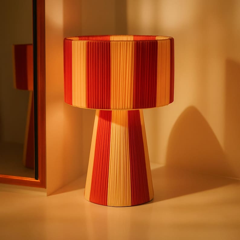 Lámpara de rafia natural con diseño de rayas rojas y crema: un toque decorativo cálido y moderno.