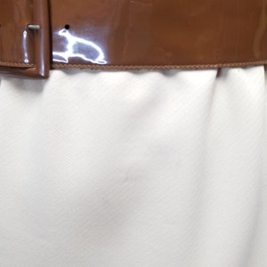 May include: A brown patent leather belt with a silver buckle.