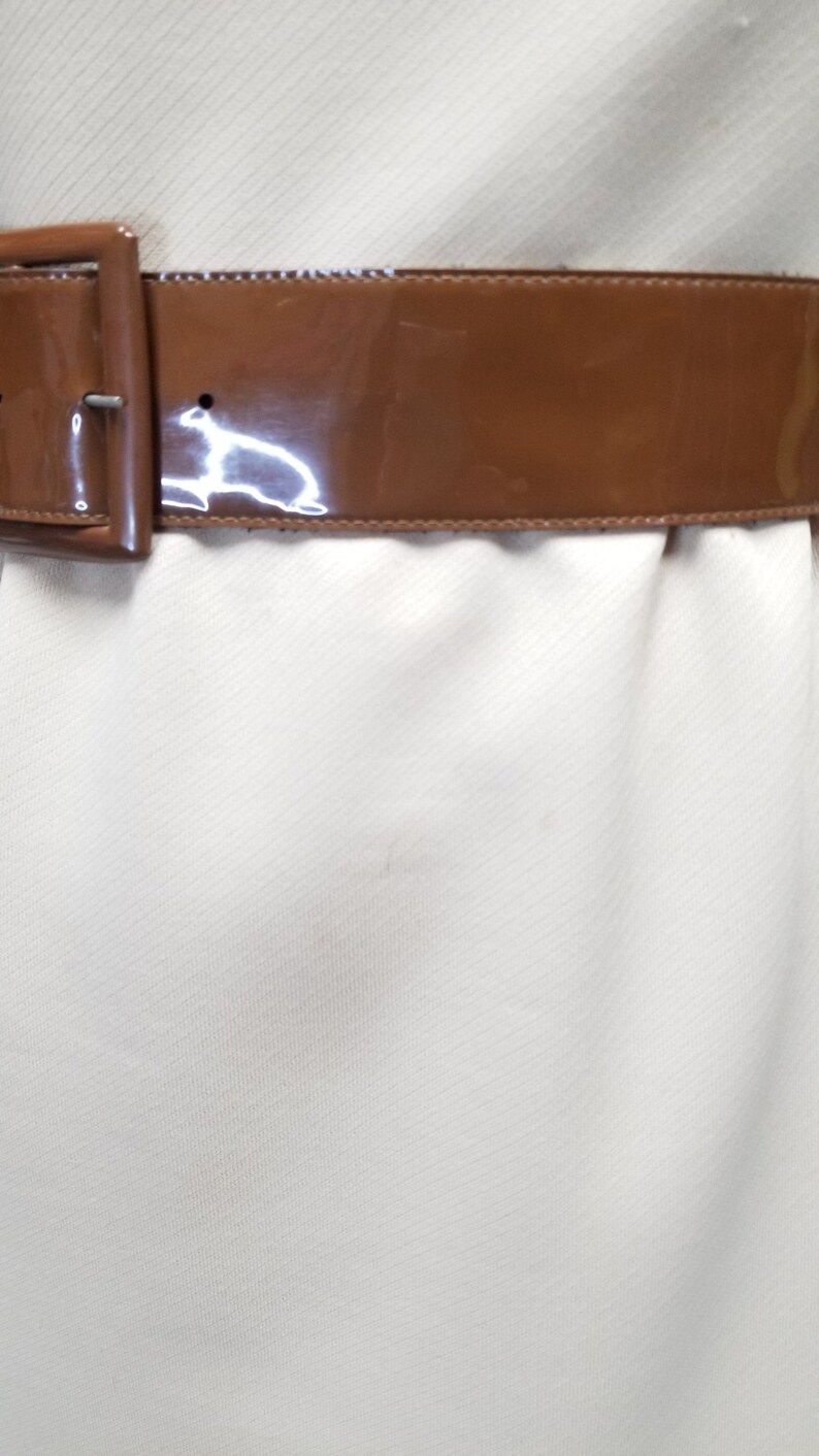 May include: A brown patent leather belt with a silver buckle.