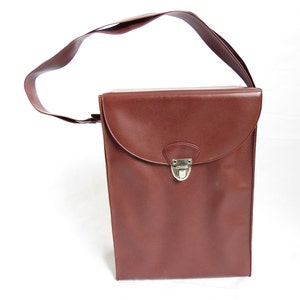 May include: A brown leather briefcase with a single strap and a metal clasp. The briefcase is closed and has a flap.