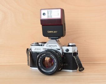 Fotocamera reflex a pellicola Canon AE-1 da 35 mm d'epoca con obiettivo da 50 mm e flash Canon Speedlite.