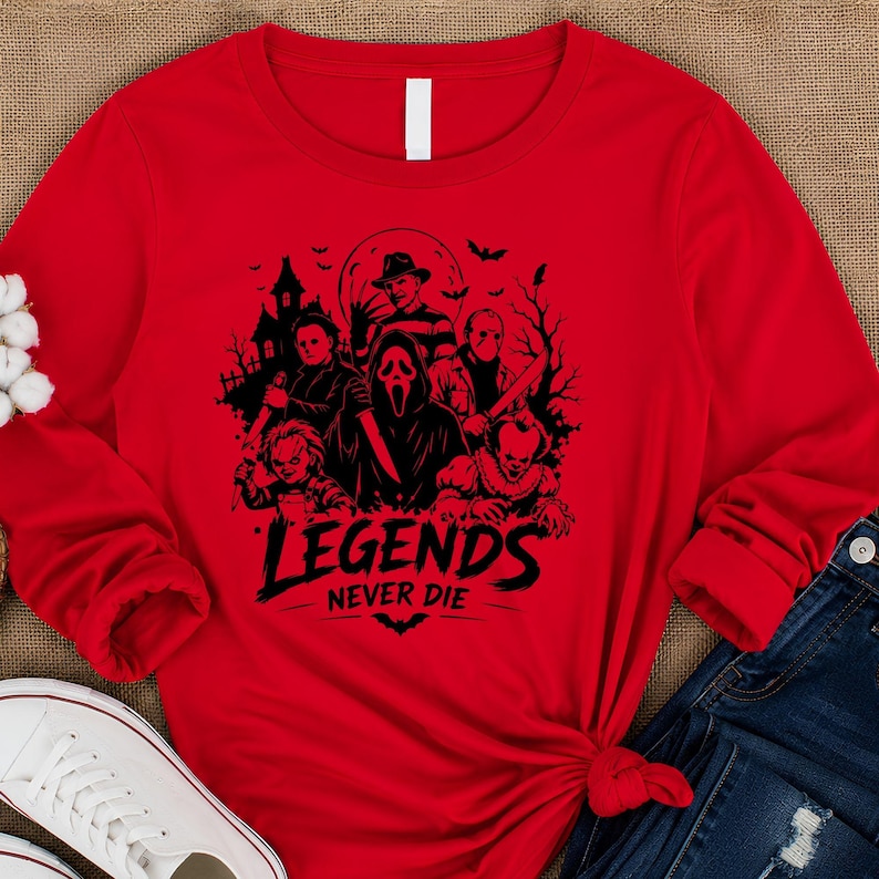 May include: A bright red long-sleeve shirt featuring a black graphic print of various horror movie characters, including a masked figure, a doll, and a clown, with the text "LEGENDS NEVER DIE" printed in a bold, stylized font below the figures.