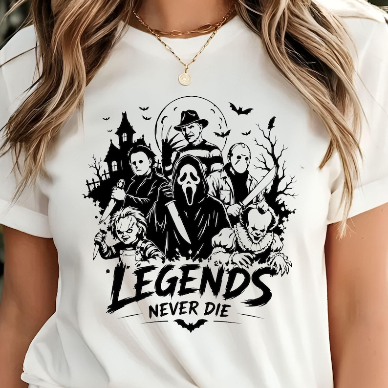 May include: A white short-sleeve t-shirt featuring a black graphic print of various horror movie characters, including a masked figure, a clown, and a man with a bladed glove. The text "LEGENDS NEVER DIE" is printed in black below the characters.