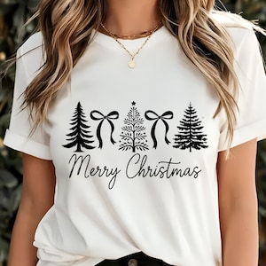 以下が含まれることがあります： クリスマスツリーとリボンの黒いグラフィックが特徴の白いTシャツ。「Merry Christmas」の文字が木の下に筆記体で書かれています。Tシャツは半袖で、クルーネックです。