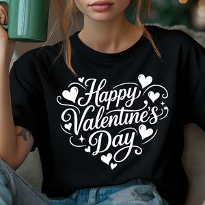 May include: Black t-shirt with a white graphic that says "Happy Valentine's Day" in a heart-shaped design. The design includes hearts and stars. The shirt is made of a soft material.