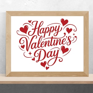 May include: A framed print with the words "Happy Valentine's Day" in red script. The text is arranged in a heart shape, with red hearts and decorative flourishes. The frame is made of light-colored wood.