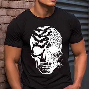 May include: Black t-shirt with a white skull design incorporating bats, a spider web, and a spider. The graphic is a Halloween-themed illustration. The shirt has a crew neck and short sleeves.