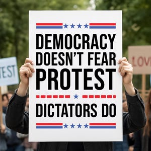 May include: A white sign with the text "DEMOCRACY DOESN'T FEAR PROTEST DICTATORS DO" in bold black letters. The sign has red and blue stripes and stars at the top and bottom. The sign is held up by a person.