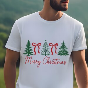 以下が含まれることがあります： クリスマスデザインの白いTシャツ。デザインには、緑のクリスマスツリー、赤いリボン、赤いスクリプトで「Merry Christmas」の文字が含まれています。シャツは柔らかい素材で作られています。