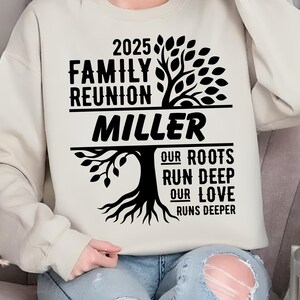 May include: A beige sweatshirt with a black graphic design. The design includes the text "2025 Family Reunion Miller" above a tree illustration, with the words "Our Roots Run Deep Our Love Runs Deeper" below.