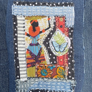 May include: A denim patch with a patchwork design. The patch features a central image of a figure in colourful clothing, surrounded by various fabric pieces with patterns like polka dots, stripes, and floral prints. A butterfly is also visible.