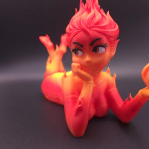 May include: A 3D-printed figurine of a reclining woman with fiery hair and a body that appears to be made of flames. The figure is colored in shades of red, orange, and yellow, with a thoughtful expression.