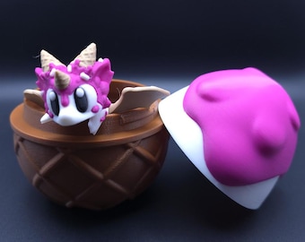 May include: A pink and white dragon figurine with a cone on its head, inside a brown waffle cone shaped container. The lid of the container is white with a pink ice cream topping.