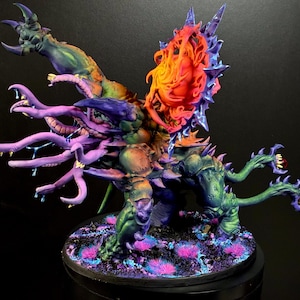 May include: A detailed, hand-painted miniature figure of a fantastical creature. The figure features a complex design with multiple arms, tentacles, and a central head with a fiery, orange and red core. The color palette includes purple, green, and blue hues.
