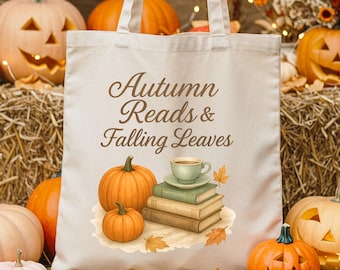 May include: A cream-coloured tote bag with the text "Autumn Reads & Falling Leaves" and a watercolour illustration of pumpkins, books, and a teacup. The image features pumpkins, hay bales, and autumn foliage, creating an autumnal theme.