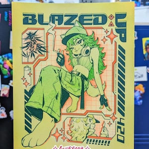 May include: A yellow poster with the words "BLAZED UP" and "420" in green and teal. The illustration features a green-haired character smoking a cigarette, wearing a hat and green clothing. The artist's name, "ASHLEYLOOB", is at the bottom.
