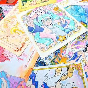 May include: A collection of colorful anime-style art prints featuring various characters and designs. The prints showcase a range of styles, including illustrations with bold outlines and vibrant colors. Some prints have text, including "NEVER KYS!" and "kill the part of you that c".