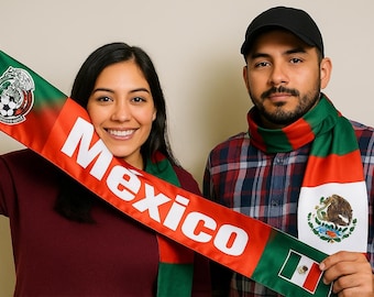 May include: A couple poses with Mexican flag scarves. The scarves are red, green, and white, with the word "Mexico" in large white letters. One scarf features the Mexican coat of arms and a soccer ball.