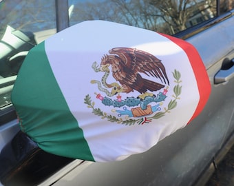 May include: A car side mirror cover featuring the Mexican flag design. The cover displays the flag's green, white, and red colors, with the Mexican coat of arms prominently displayed on the white section.