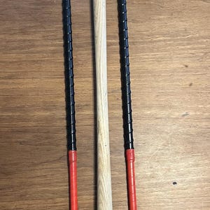 Könnte beinhalten: Drei Holzstäbe mit schwarzen und roten Spitzen. Die Stäbe liegen auf einer Holzoberfläche.