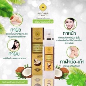 May include: A product advertisement for Pinnara Coconut Oil Serum. The image features a bottle of serum, a box, and illustrations of coconuts and leaves. Text in Thai describes the serum's benefits for skin, hair, and feet.