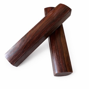 May include: Two rectangular wooden blocks with rounded edges. The blocks are a rich, dark brown color with visible wood grain. They are positioned diagonally against a white background.