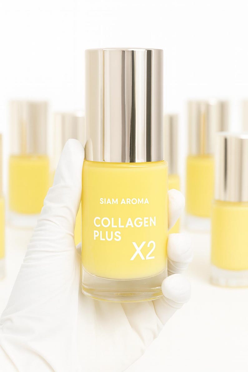 May include: A yellow bottle of "Collagen Plus X2" serum is held by a gloved hand. The bottle has a silver cap and the brand name "SIAM AROMA" is printed on the front. Other bottles are visible in the background.