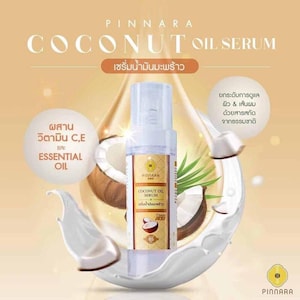 May include: A product advertisement for Pinnara Coconut Oil Serum. The image features a clear bottle of serum with a white and gold label, set against a backdrop of coconuts, coconut milk, and text in English and Thai. The text highlights the serum's ingredients and benefits.