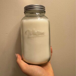 May include: A clear glass jar with a silver lid filled with a white substance. The jar has the word "Ball" embossed on the side.