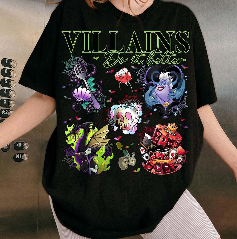 May include: Black t-shirt with the text "VILLAINS Do it better" in green. The shirt features colorful illustrations of various Disney villains, including Ursula, Maleficent, and the Queen of Hearts, surrounded by spiderwebs and bats.