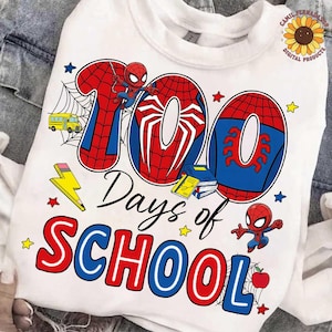 May include: White t-shirt with a colourful graphic celebrating "100 Days of School." The design includes the number "100" in red and blue, Spider-Man illustrations, stars, a school bus, books, and the words "Days of School."