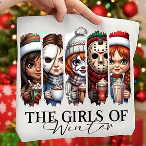 May include: White tote bag featuring cartoon illustrations of horror movie characters in winter attire, each holding a warm beverage. The text "THE GIRLS OF Winter" is printed in black script below the illustrations.
