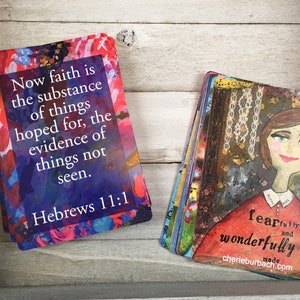 May include: A stack of colorful cards with inspirational quotes and artwork. The top card features a quote from Hebrews 11:1, "Now faith is the substance of things hoped for, the evidence of things not seen." The bottom card features a painting of a woman with the text "fearfully and wonderfully made" and a website address.