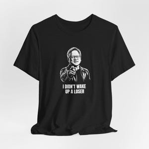May include: Black t-shirt featuring a black and white illustration of a man pointing. The text "I DIDN'T WAKE UP A LOSER" is printed below the illustration. The t-shirt is made of a soft material.