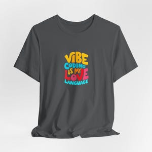 May include: Dark gray t-shirt with a colorful graphic that says "VIBE CODING IS MY LOVE LANGUAGE".