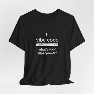 Op de afbeelding: Zwart T-shirt met witte tekst die "I vibe code" luidt en een witte zoekbalk met de tekst "what's your superpower?"