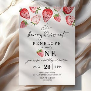 May include: A white invitation card with a strawberry theme. The text reads "Our berry sweet Penelope is turning one. Join us for a birthday celebration. Aug 23 | 1 PM. Penelope's Home 123 Main Street, New York, NY. RSVP to Andrea 123456789".