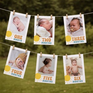 May include: A string of six photos of babies, each clipped to a string with wooden clothespins. Each photo has a sun graphic and text indicating the baby's age in months: One, Two, Three, Four, Five, and Six Months.