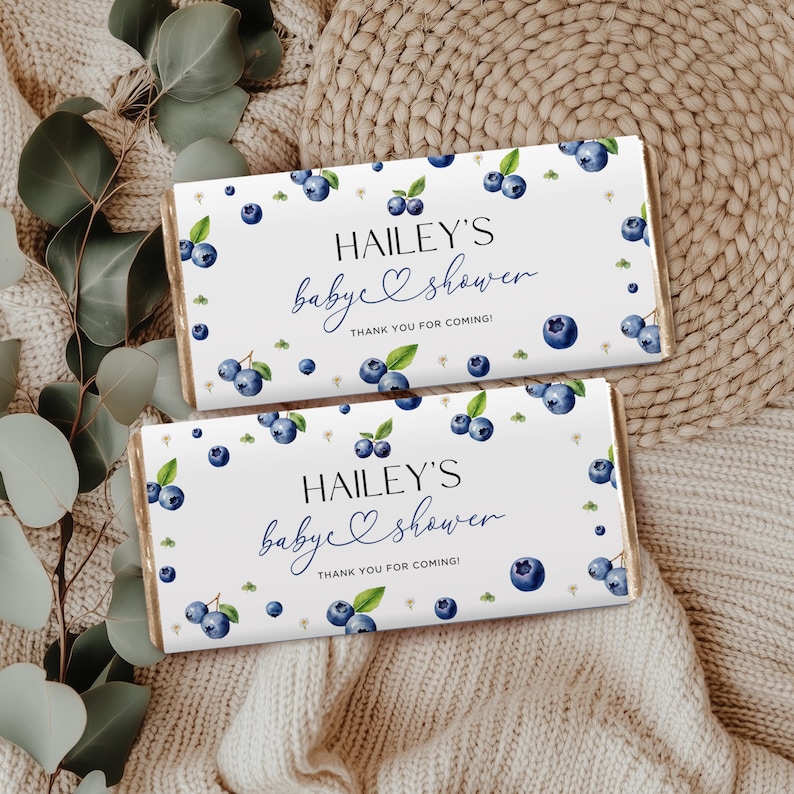May include: Two rectangular baby shower favors with white backgrounds. The favors are decorated with watercolor blueberries and green leaves. The text "HAILEY'S baby shower THANK YOU FOR COMING!" is printed on the front.